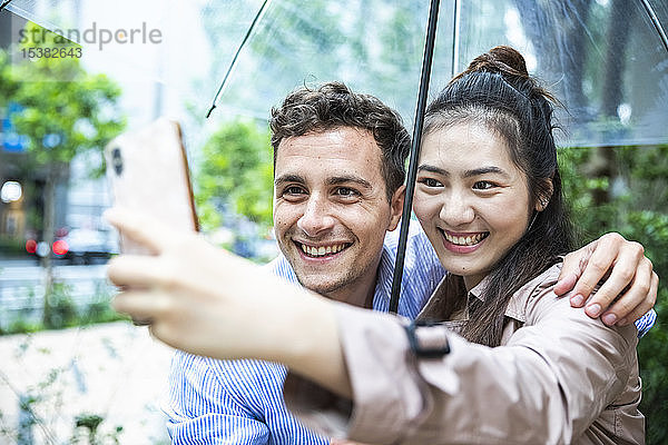 Glückliches Paar mit Regenschirm beim Selfie in Ginza  Tokio  Japan