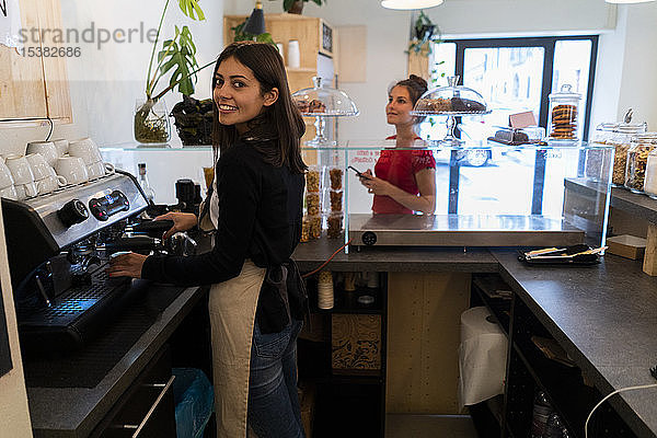 Porträt einer lächelnden jungen Frau  die in einem Café einen Kaffee trinkt