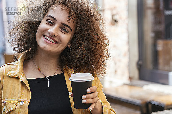 Porträt einer glücklichen Teenagerin mit Kaffee zum Mitnehmen