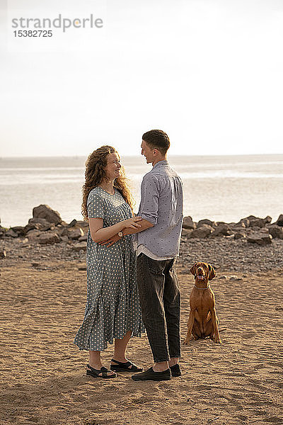 Junges Paar mit Hund am Strand