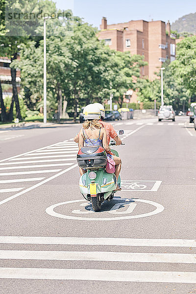 Junges Ehepaar fährt einen Oldtimer-Motorroller auf einer Stadtstraße
