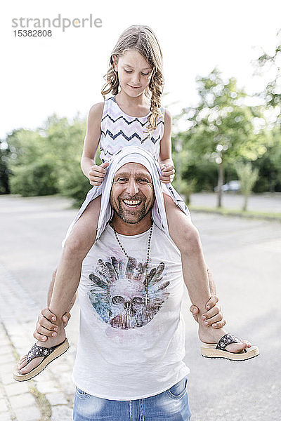 Vater trägt verspielte Tochter auf den Schultern