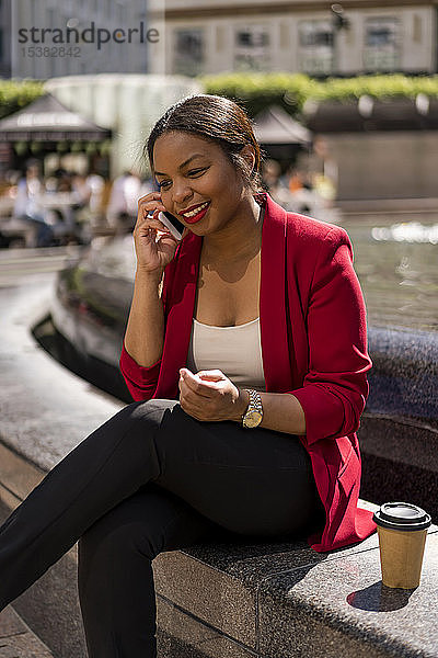 Porträt einer lächelnden Geschäftsfrau am Telefon  London  UK