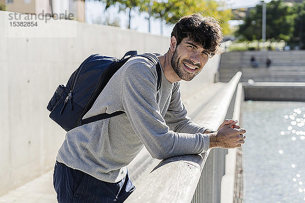 Porträt eines lächelnden Mannes mit Rucksack bei einer Pause in der Stadt