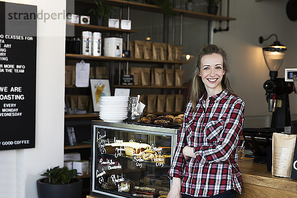 Porträt einer lächelnden Frau an der Theke eines Cafés