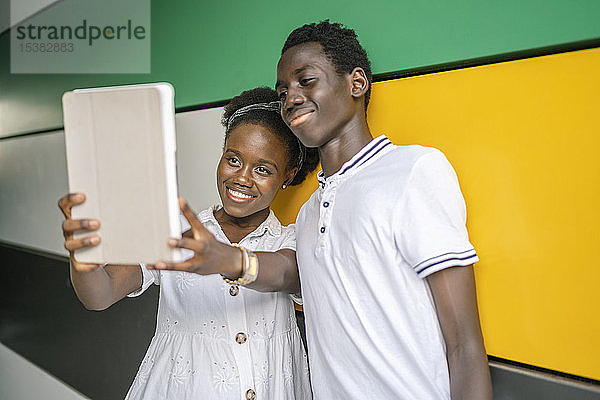 Porträt eines glücklichen jungen Paares  das sich mit einem digitalen Tablet selbstständig macht