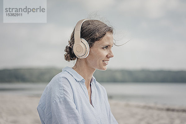 Frau beim Musikhören mit Kopfhörern am Meer  poartrait