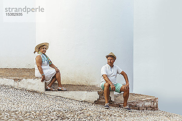 Älteres Touristenpaar  das auf Stufen in einem Dorf sitzt  El Roc de Sant Gaieta  Spanien