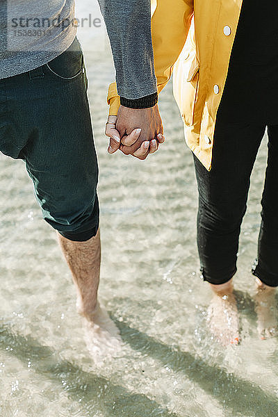 Paar hält sich am Strand an den Händen