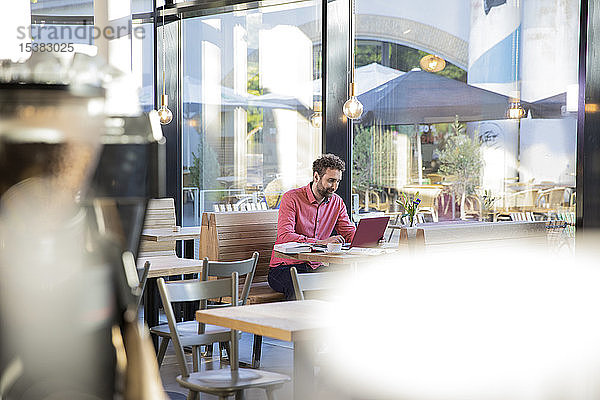 Junger Mann benutzt Laptop in einem Café