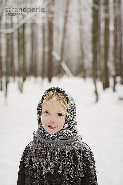 Bildnis eines kleinen Mädchens mit Kopftuch vor dem Winterwald stehend