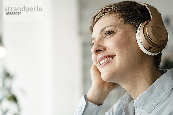 Porträt einer glücklichen Geschäftsfrau  die mit Kopfhörern Musik hört