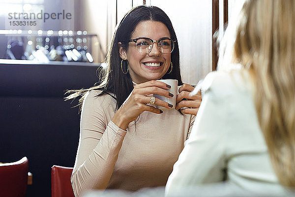 Porträt einer lächelnden Frau mit Freundin in einem Cafe