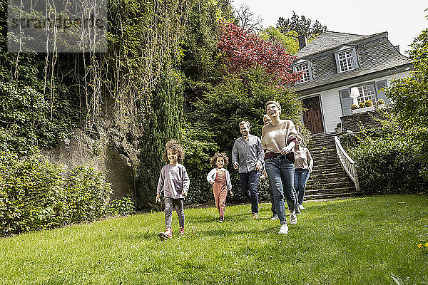 Glückliche Großfamilie beim Spaziergang im Garten ihres Hauses