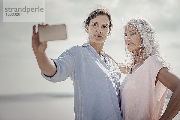 Mutter und Tochter verbringen einen Tag am Meer  nehmen sich ein Smartphone