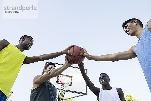 Gruppe gemischtrassiger Männer  die alle zusammen Basketball halten  niedriger Blickwinkel
