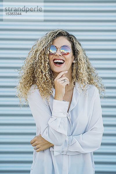 Porträt einer lachenden jungen Frau mit Sonnenbrille