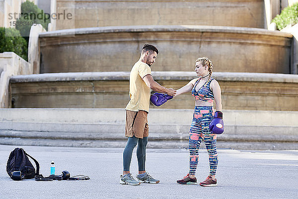 Fitnesstrainer übt Boxunterricht mit einer jungen Frau im Freien in der Stadt  die einen Boxhandschuh anzieht
