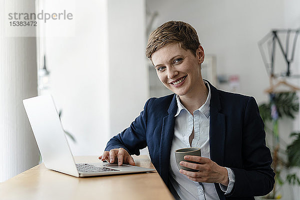 Porträt einer lächelnden Geschäftsfrau mit Laptop in einem Cafe