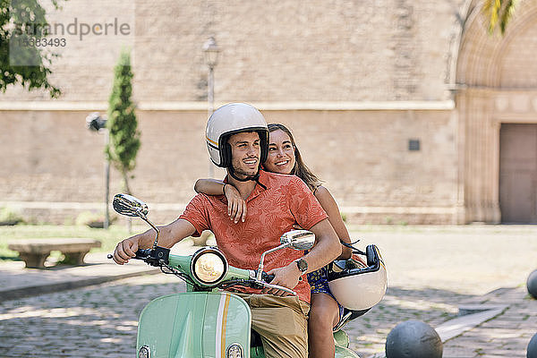 Junges Paar auf einem Oldtimer-Motorroller im Freien