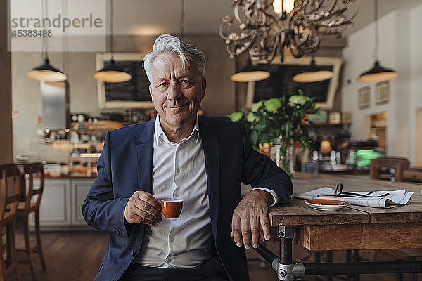 Porträt eines hochrangigen Geschäftsmannes  der in einem Café Espresso trinkt