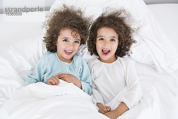 Porträt von zwei glücklichen Zwillingsbrüdern im Bett liegend