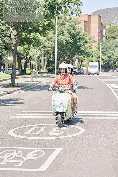 Junges Ehepaar fährt einen Oldtimer-Motorroller auf einer Stadtstraße