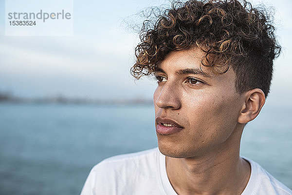 Porträt eines jungen Mannes mit lockigem Haar am Meer
