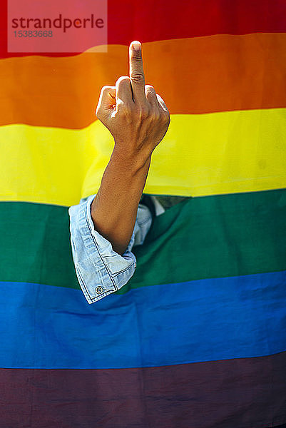 Frau zeigt den Finger vor einer Regenbogenfahne