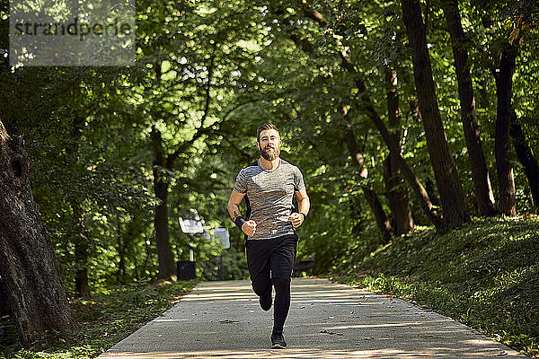 Sportlicher Mann rennt auf Waldweg