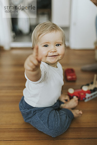 Lächelndes kleines Mädchen zeigt mit dem Finger nach Hause