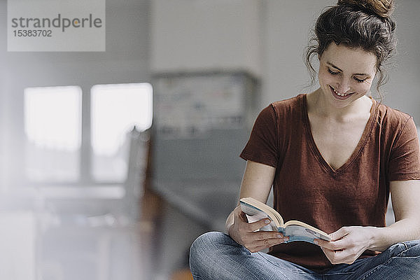 Lächelnde junge Frau liest ein Buch