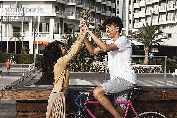 Junges Paar mit Fahrrad  High-Five in der Stadt