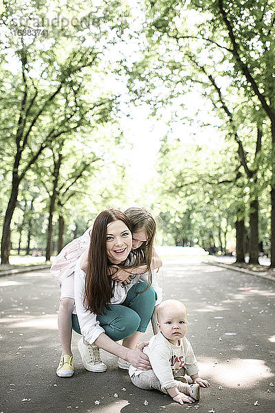 Lächelnde Mutter mit ihren beiden Kindern im Park