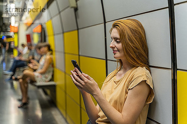 Frau benutzt Smartphone in U-Bahn-Station