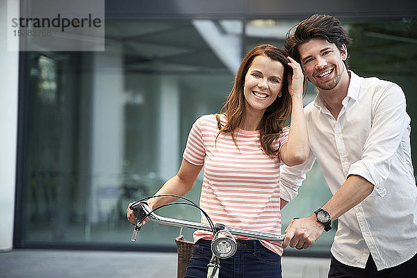 Porträt eines glücklichen Paares mit Fahrrad in der Stadt