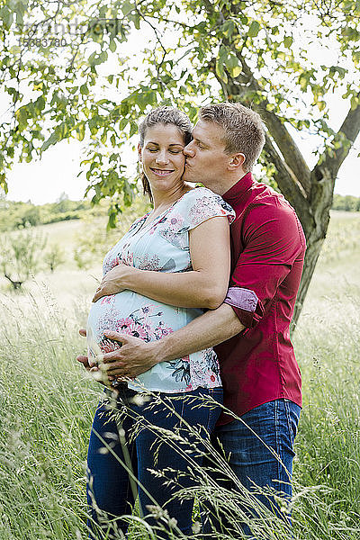 Schwangere Frau und Mann halten Babybauch  Mann küsst seine Frau