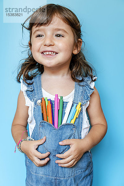 Porträt eines süßen kleinen Mädchens mit farbigen Kugelschreibern auf der Tasche