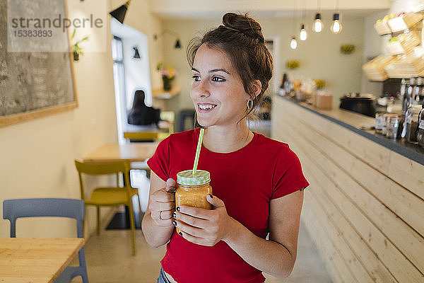 Porträt einer jungen Frau mit einem Smoothie in einem Cafe