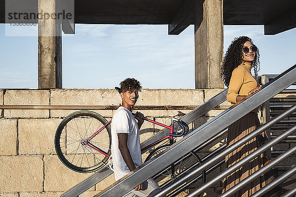 Junges Paar beim Treppensteigen  Fahrrad tragend