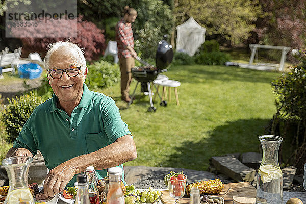 Porträt eines glücklichen älteren Mannes beim Mittagessen im Garten