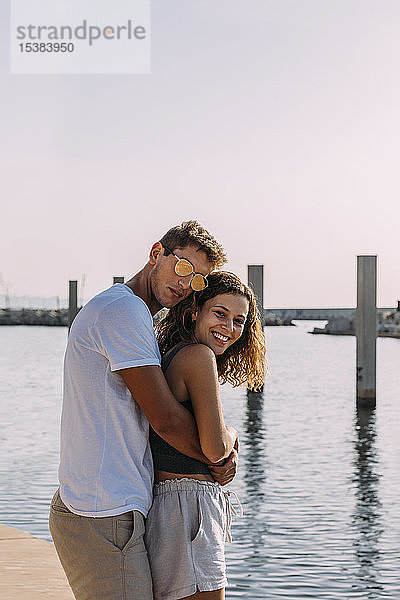Glückliches junges Paar umarmt sich am Meer