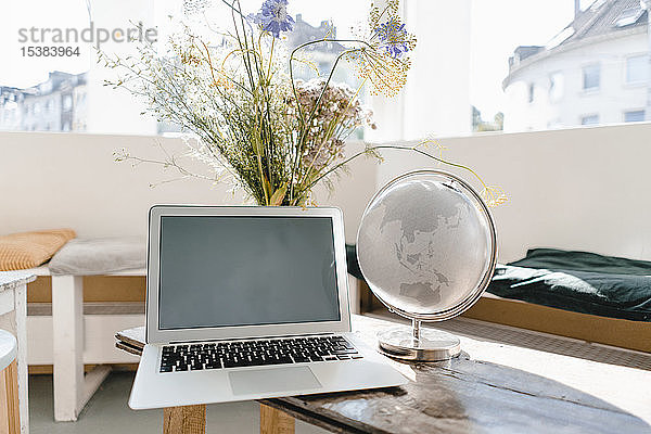 Laptop und Globus auf einem Tisch in einem Café