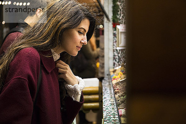 Junge Frau kauft auf dem Weihnachtsmarkt ein