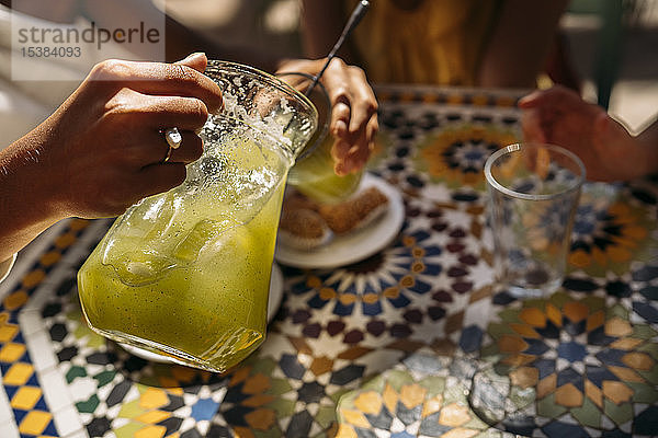 Frau serviert ihren Freunden Limonade in einem marokkanischen Café