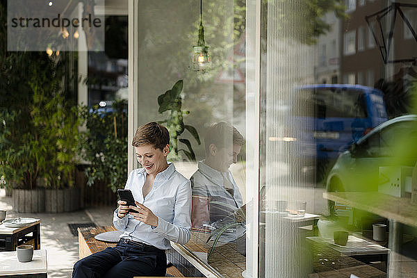 Geschäftsfrau benutzt Mobiltelefon in einem Café