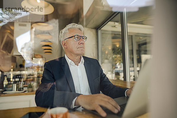 Leitender Geschäftsmann benutzt Laptop in einem Café