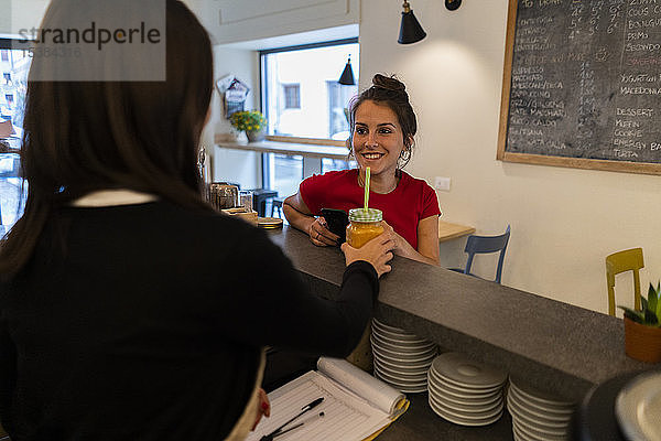 Lächelnde junge Frau an der Theke eines Cafés
