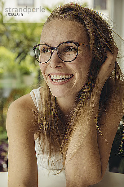Porträt einer glücklichen jungen Frau mit Brille  die zur Seite schaut