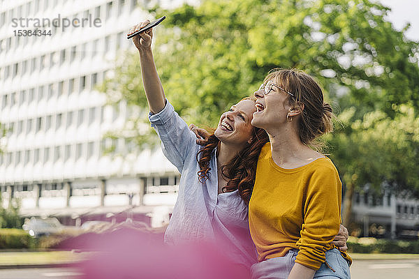 Zwei glückliche Freundinnen  die in der Stadt ein Selfie machen